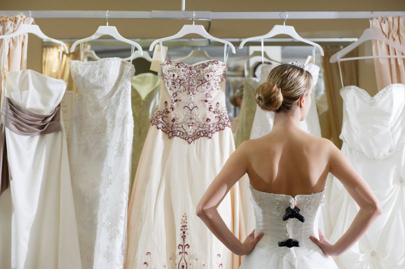 0 Bride looking at rack of dresses