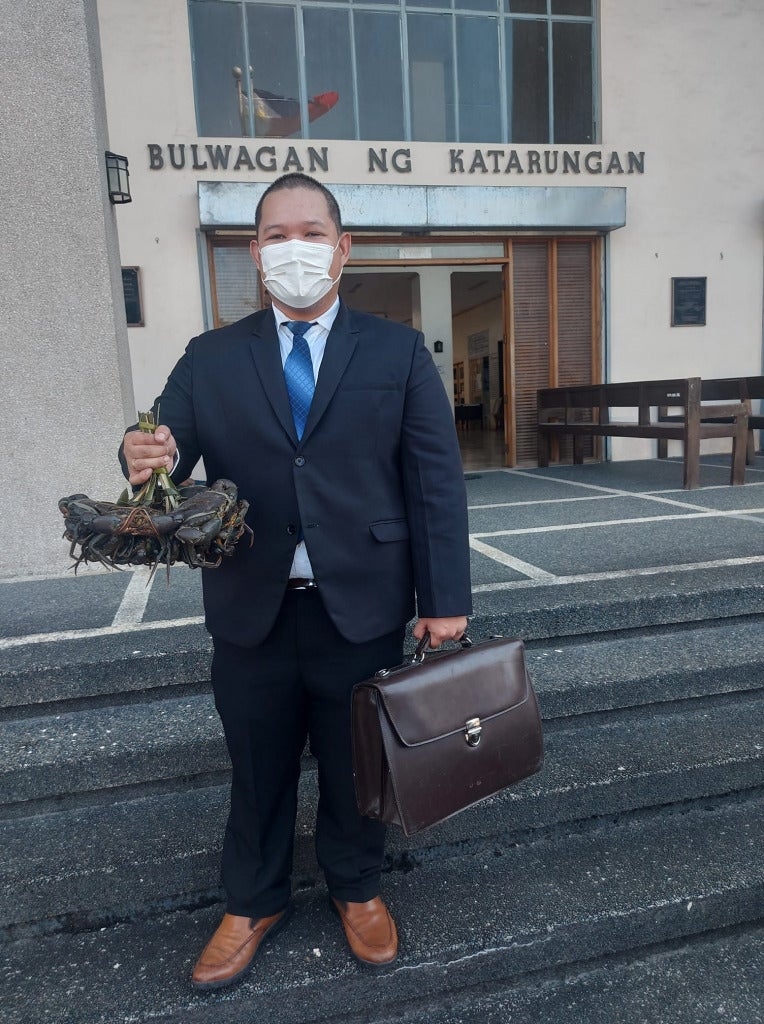 laywe holding crab and briefcase standing in front of court room