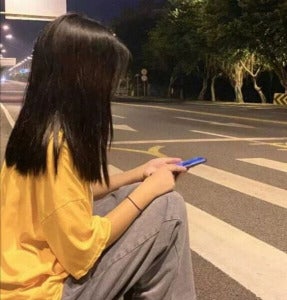 女子拿着手机站在路旁