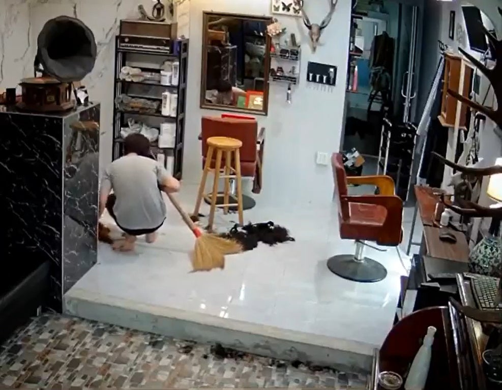 SS 2 Man plays with cat while sweeping the floor in a hair salon