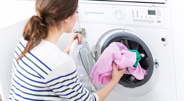 woman putting shirt into washing machine