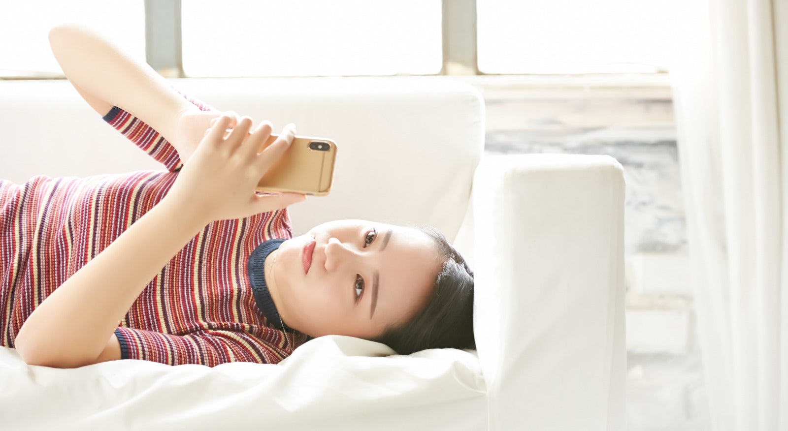 woman laying sofa holding phone