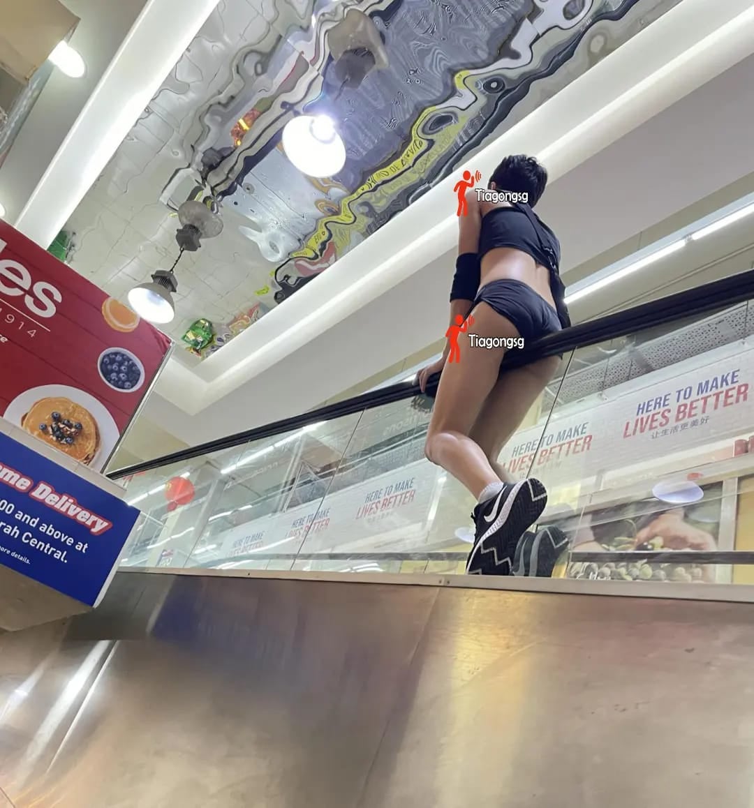 man rides escalator singapore wearing shorts and crop top 2