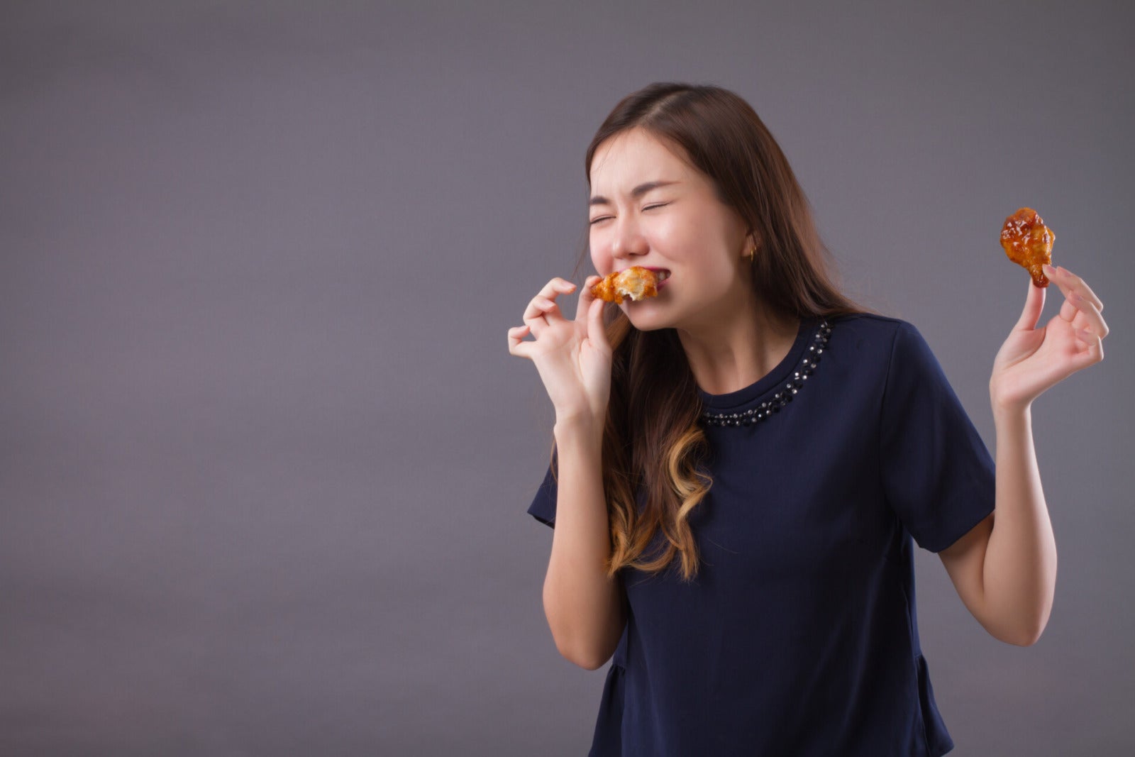 asian woman eating chicken drumstick happy 123rf