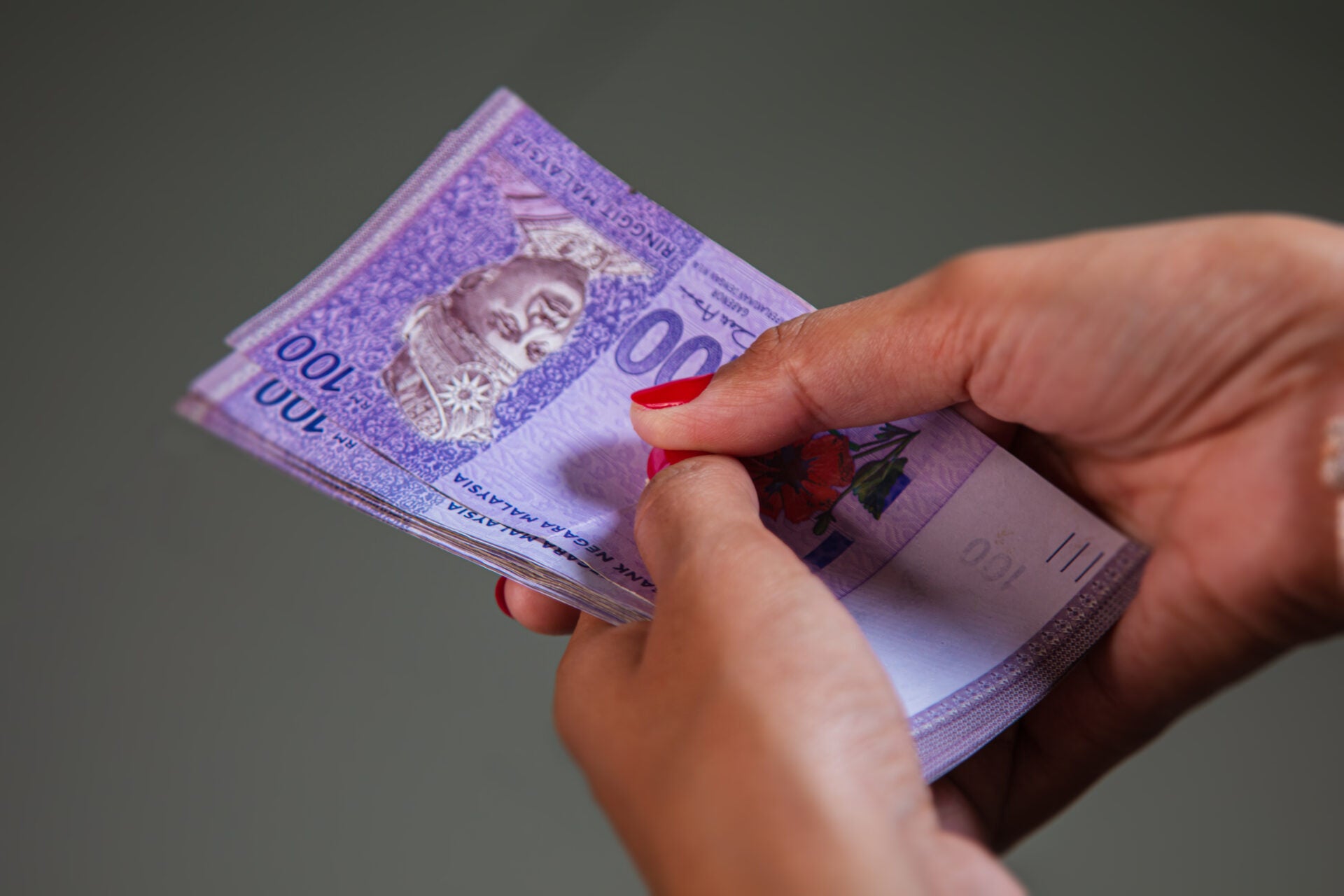 woman holding rm100 banknotes 123rf
