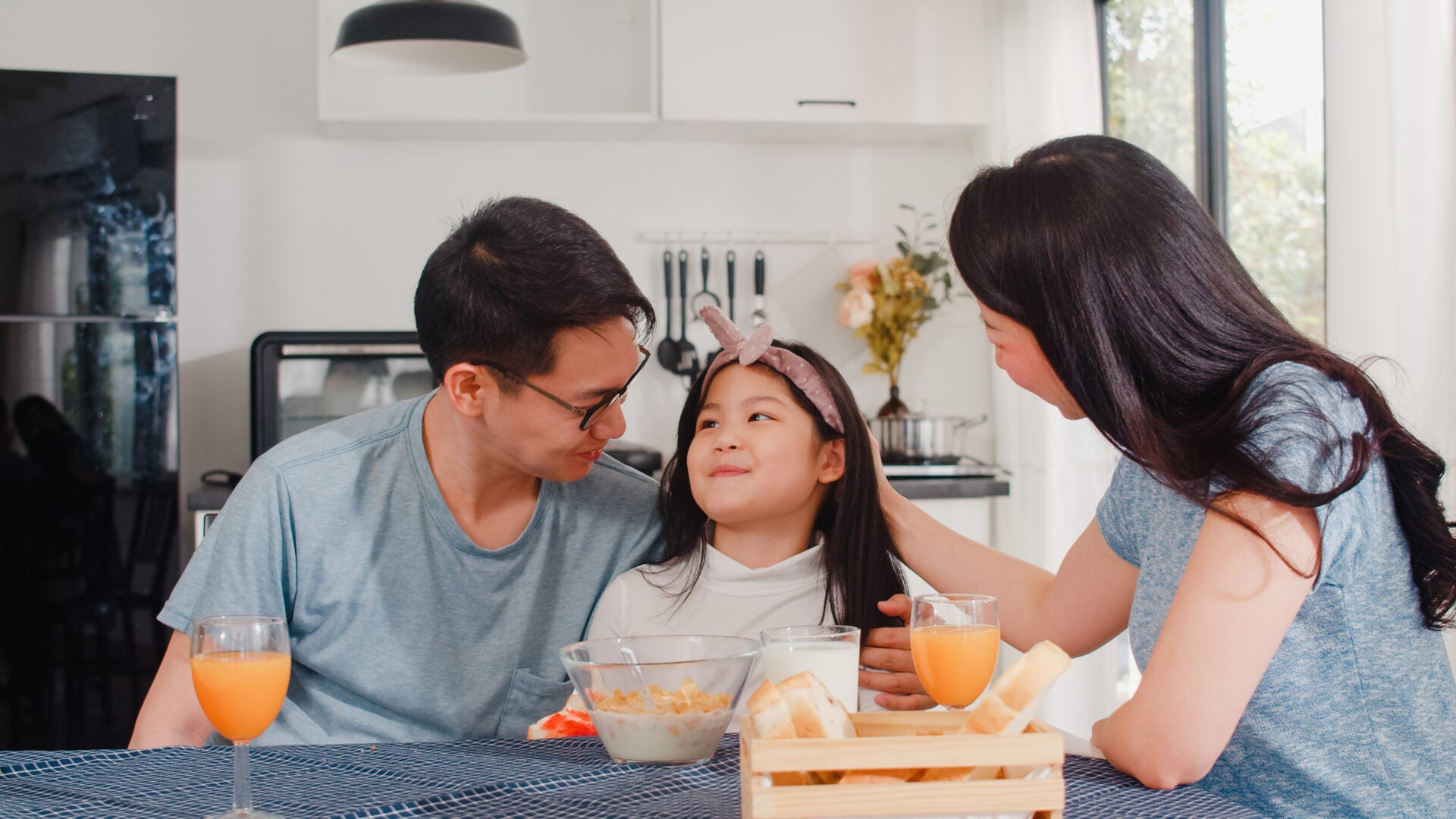 asian japanese family has breakfast home asian mom dad daughter feeling happy talking together while eat bread corn flakes cereal milk bowl table kitchen morning