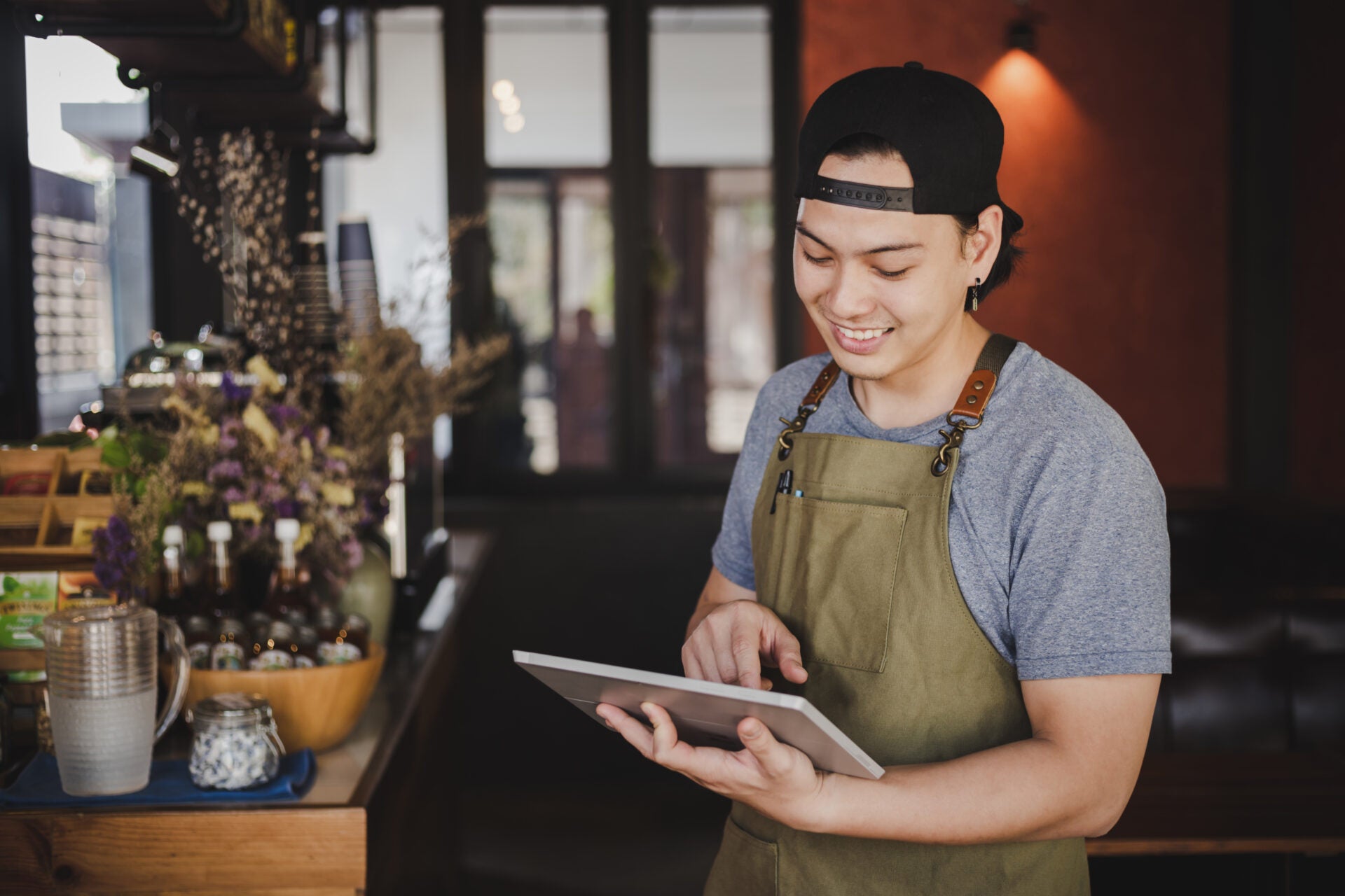 asian man barista holding tablet checking order from customer coffee cafe