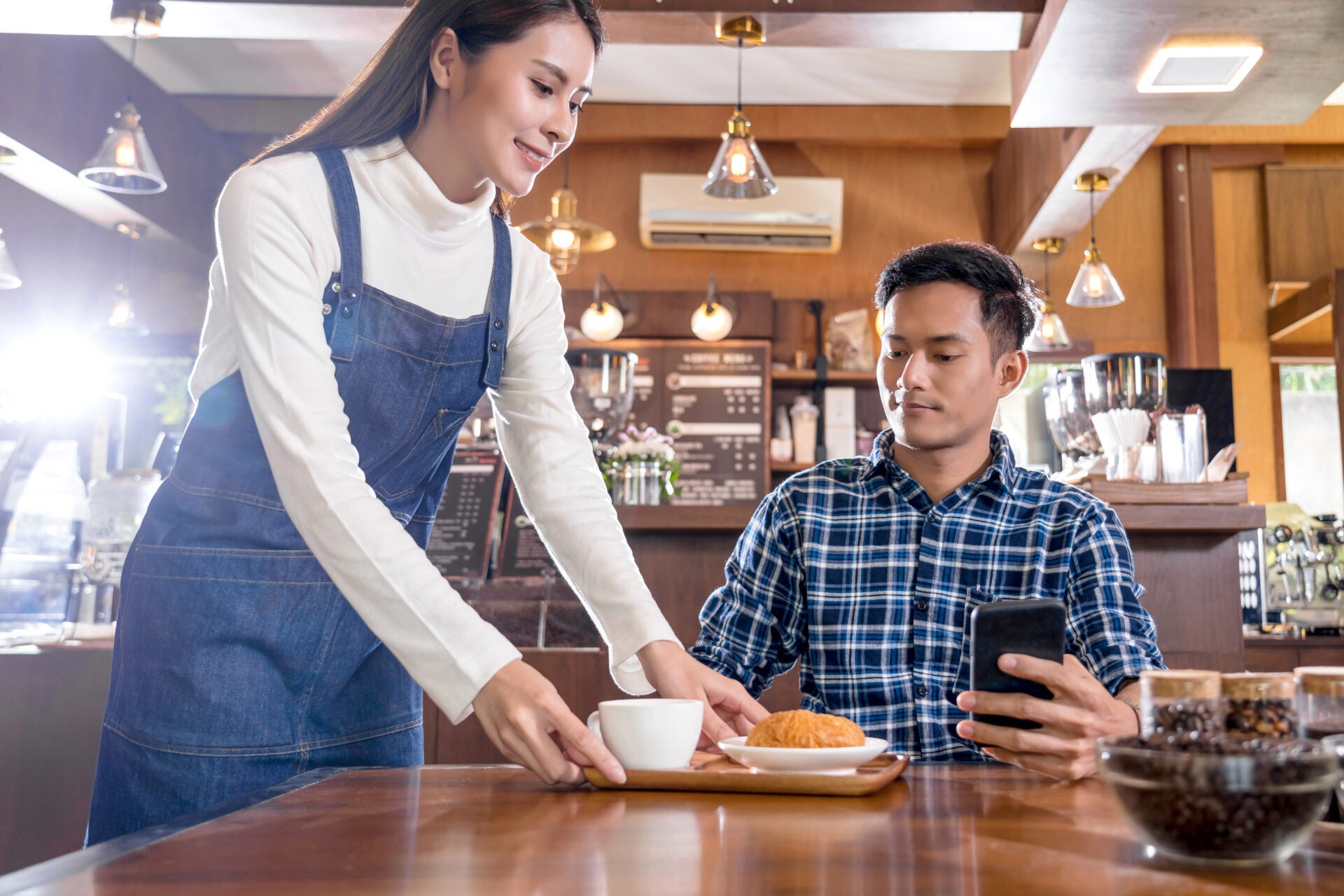 asian barista small business owner serving cup coffee
