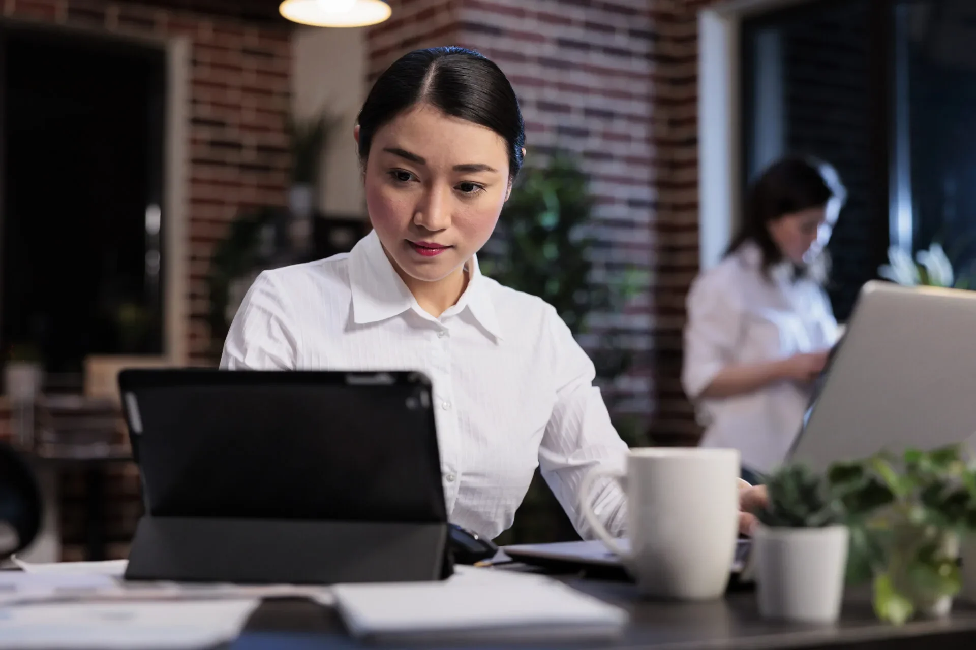 Asian Businesswoman With Modern Tablet Reviewing Accounting Documentation Office Workspace Executive Manager Working Electronic Touchscreen Device While Developing Marketing Strategy
