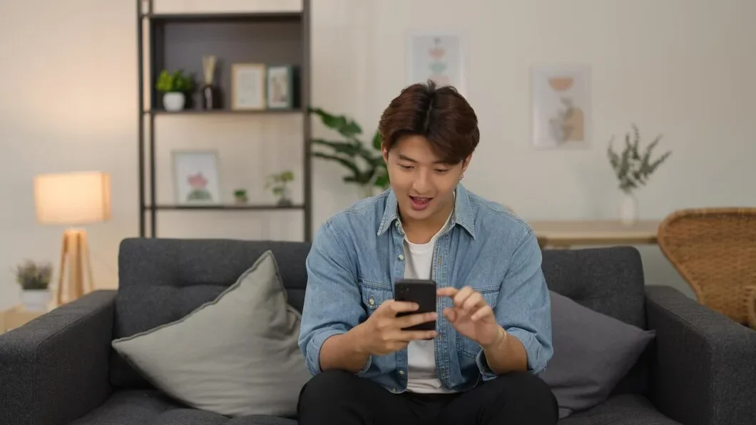 Young Asian Man Smiling While Using Smartphone Living Room Sofa 1308 188892